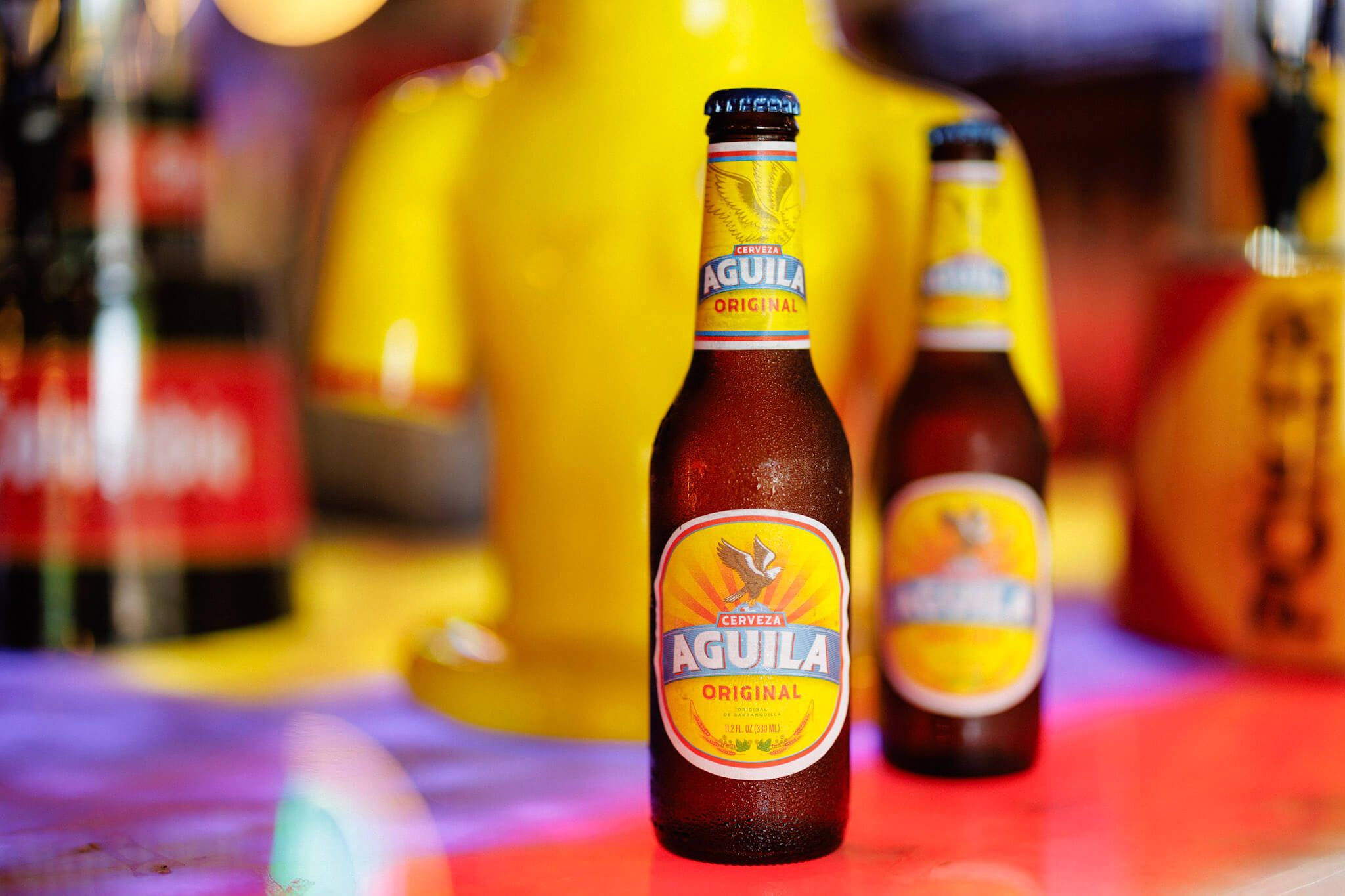 Two bottles of Cerveza Aguila Original beer standing on a surface.