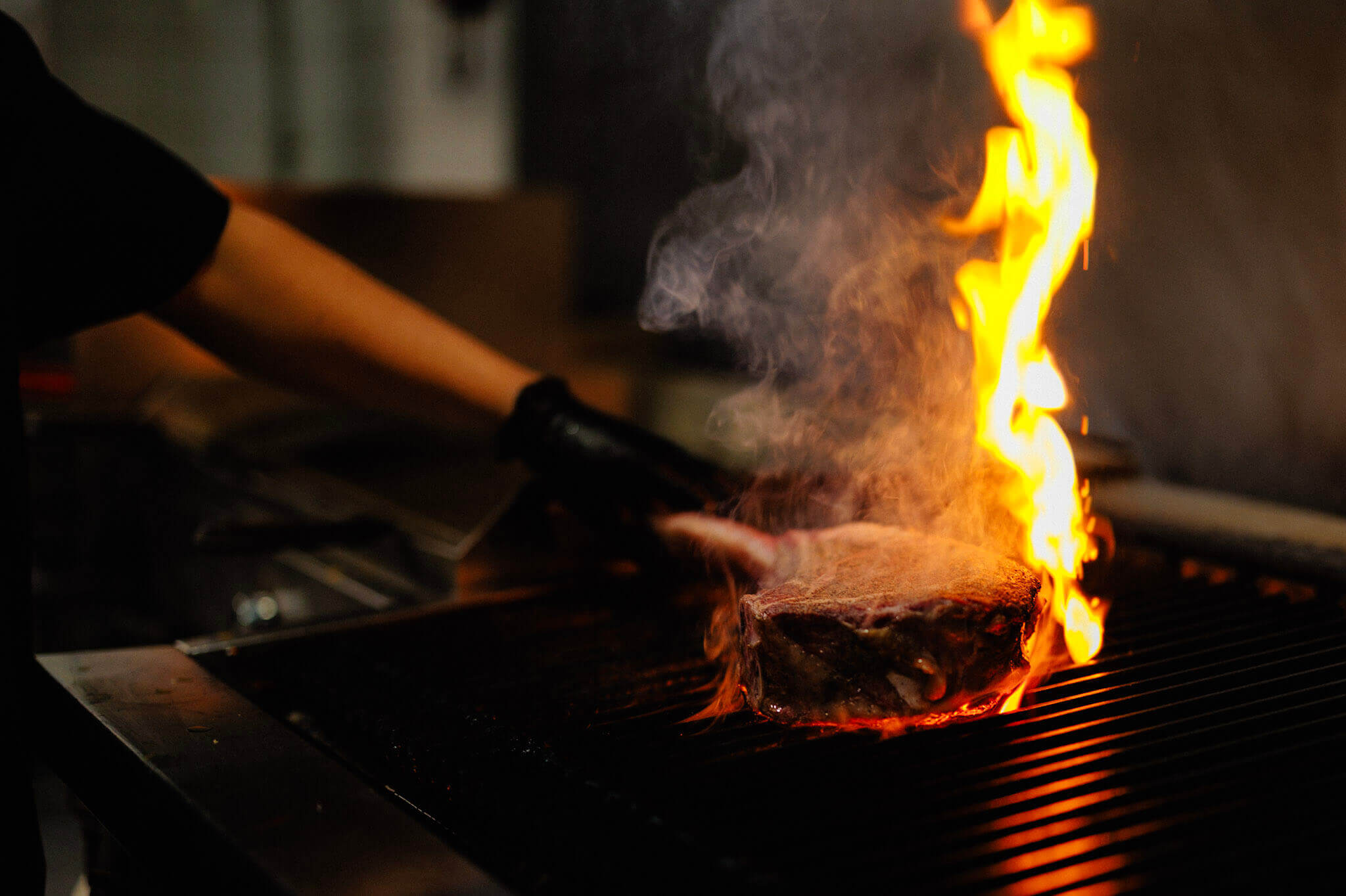 A thick steak seared by flames on a grill.